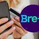 Un amujer pagando por celular junto al logo de Bre-B. 