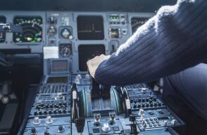 A pilot's hand on the throttle of a plane.