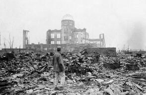 En esta imagen, tomada el 8 de septiembre de 1945, un reportero extranjero de pie sobre los escombros ante los restos de un edificio que en su día fue un centro de exposiciones y sede gubernamental en Hiroshima, Japón, un mes después del lanzamiento de