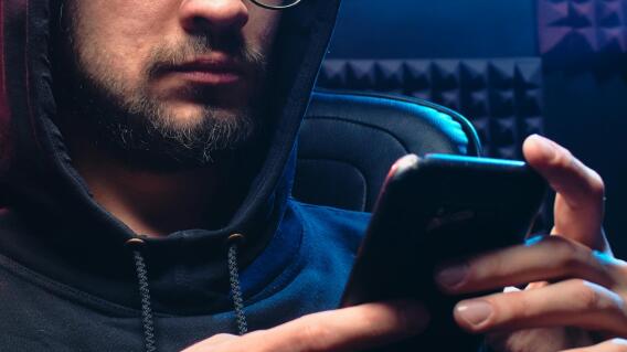 Hombre con un celular haciendo una estafa por redes sociales. 