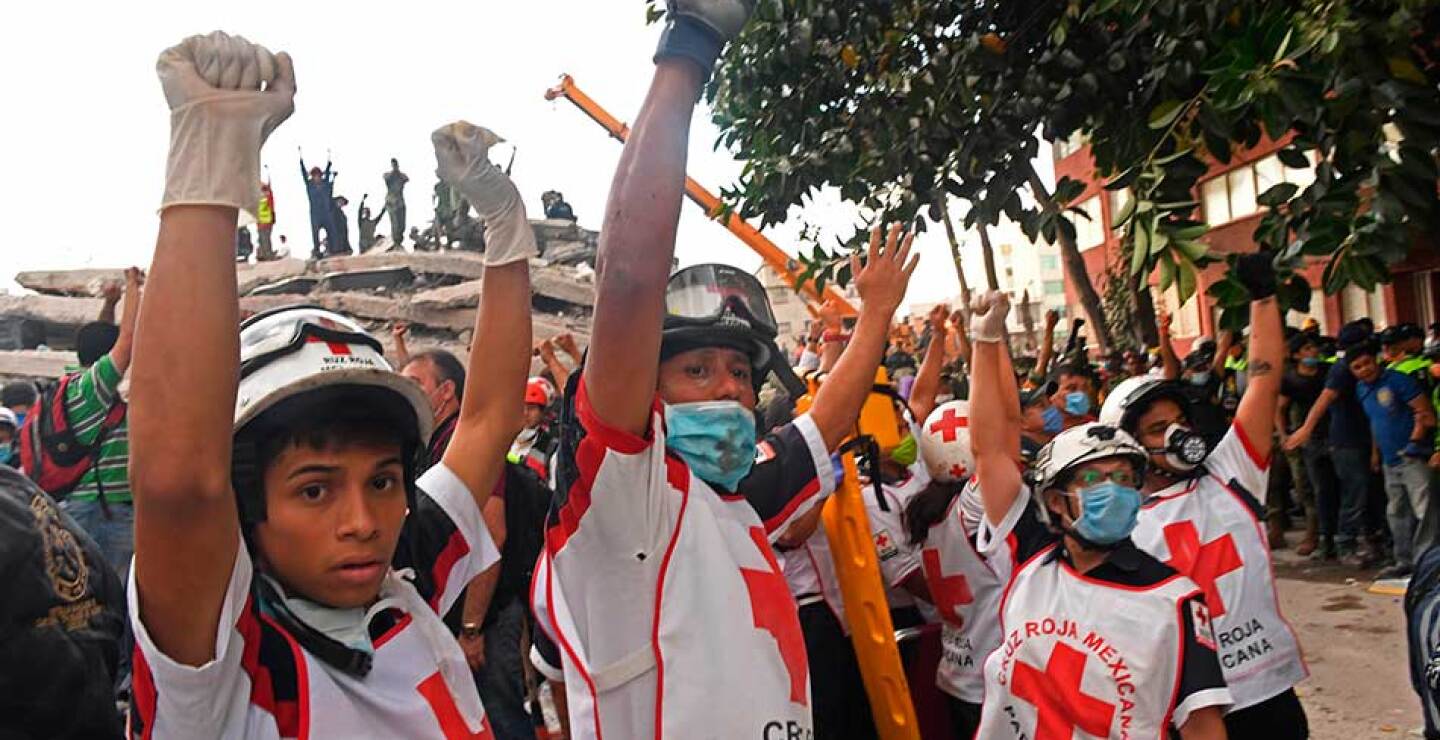 Paramédicos de la cruz roja mexicana piden silencio para escuchar posible gritos de gente atrapada bajo las estructuras colapsadas.