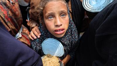 Una niña palestina sostiene un contenedor en un punto de distribución de alimentos en el campamento de refugiados de Nuseirat, en el centro de la Franja de Gaza, el 21 de mayo de 2025. Una niña palestina sostiene un contenedor en un punto de distribución de alimentos en el campamento de refugiados de Nuseirat, en el centro de la Franja de Gaza, el 21 de mayo de 2025.
