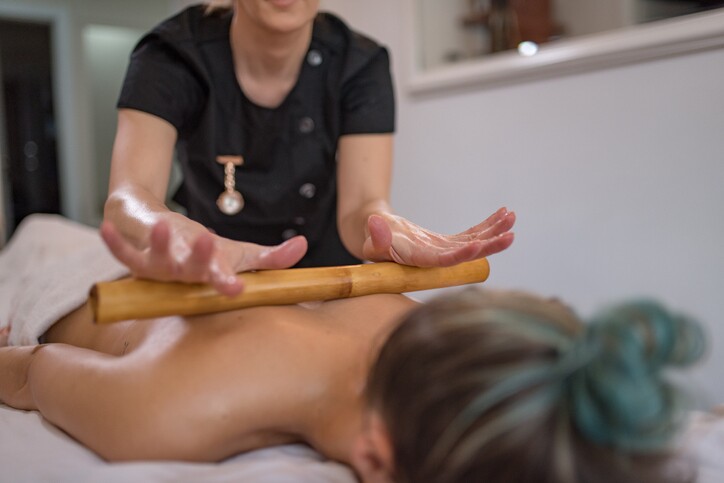 Woman is getting massage with bamboo stick in spa