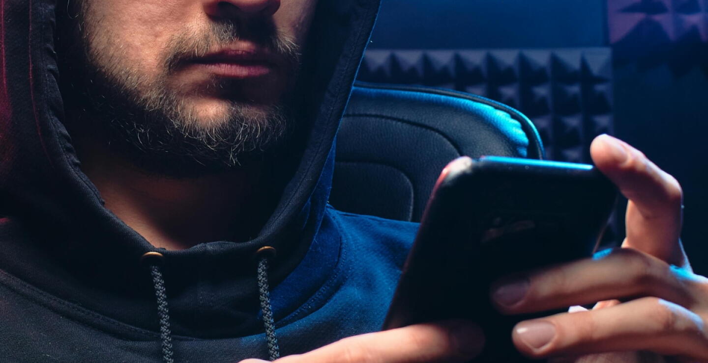 Hombre con un celular haciendo una estafa por redes sociales. 