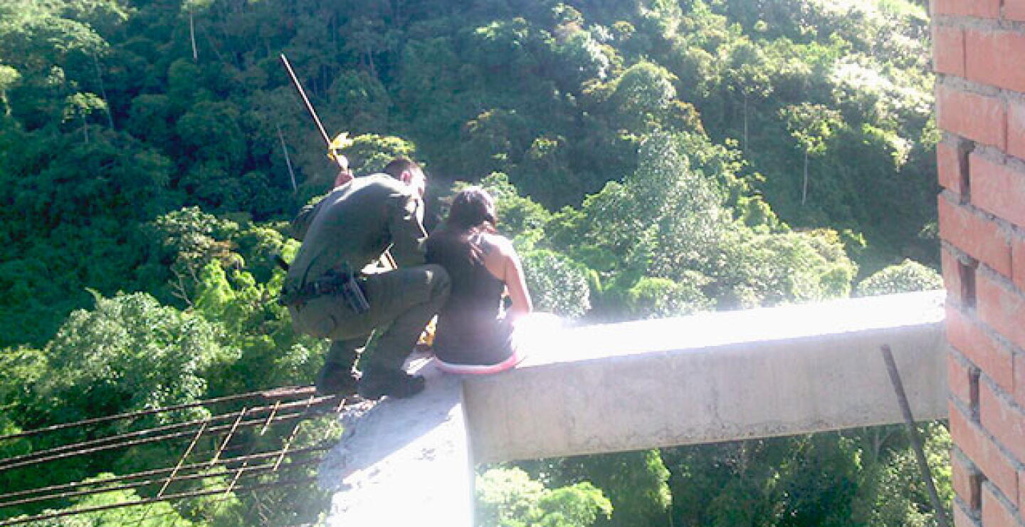 Momento en que un patrullero de la Policía convence a una mujer de no arrojarse al vacío. Foto: Alcaldía de Envigado.