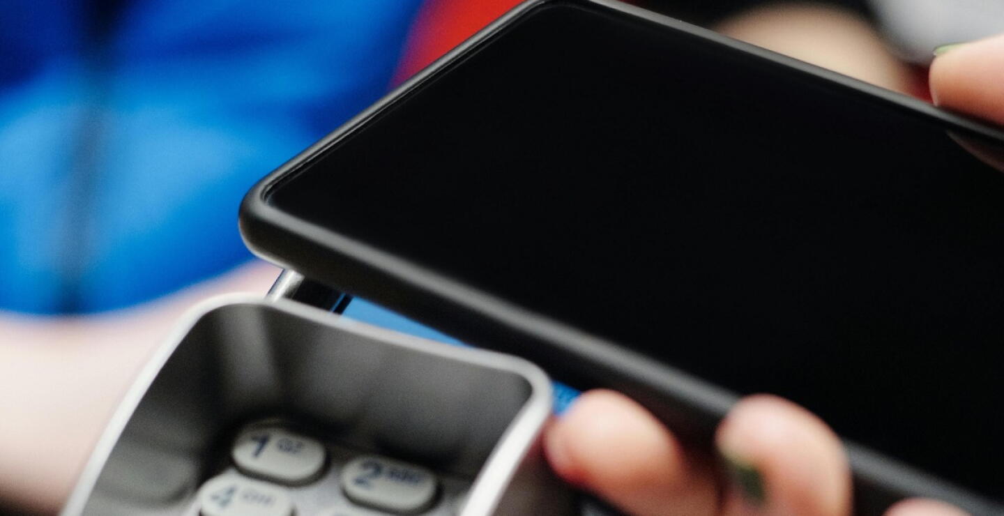 Celular encima de un datafono para realizar un pago. 
