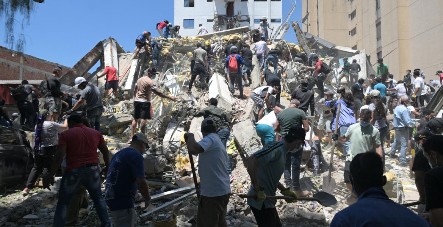 Personas buscan sobrevivientes entre los escombros de un edificio derrumbado en Cali
