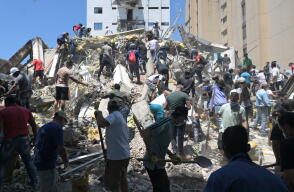 Personas buscan sobrevivientes entre los escombros de un edificio derrumbado en Cali
