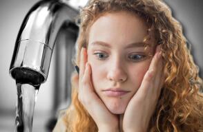 Mujer preocupada con un grifo de agua atrás. 