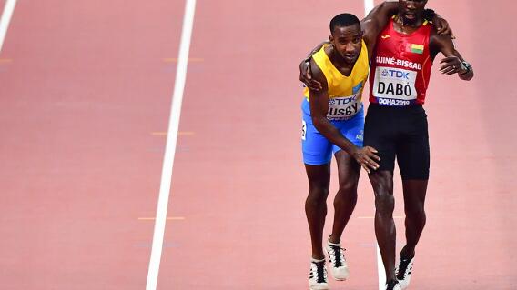 344598_Un atleta agotado llega a la meta sostenido por un rival / Foto: AFP