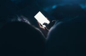 Woman texting and reading on smartphone in bed