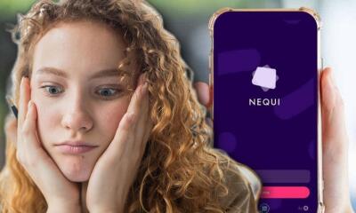 Mujer junto a un celular usando Nequi. 