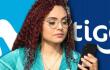 Mujer con su celular y las marcas de Movistar y Tigo. 
