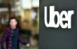 Un logotipo de Uber se ve en un cartel fuera de la sede de la compañía mientras personas protestan cerca en San Francisco, California, el 8 de mayo de 2024. 