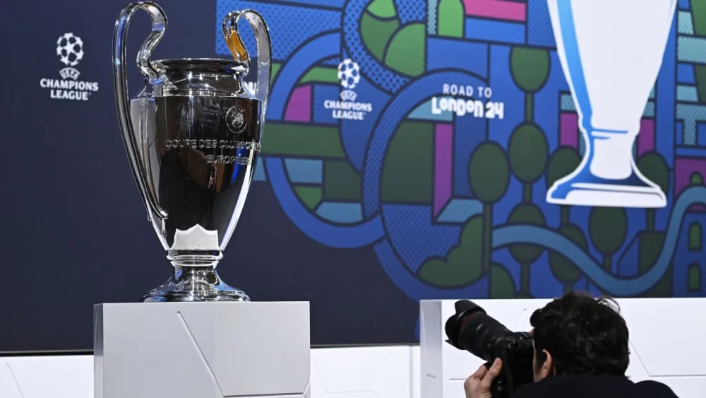 A man takes a photograph of the UEFA Champions League trophy ahead of the 2023-2024 UEFA Champions League football tournament round of 16 draw at the House of European Football in Nyon, on December 18, 2023. A man takes a photograph of the UEFA Champions League trophy ahead of the 2023-2024 UEFA Champions League football tournament round of 16 draw at the House of European Football in Nyon, on December 18, 2023.