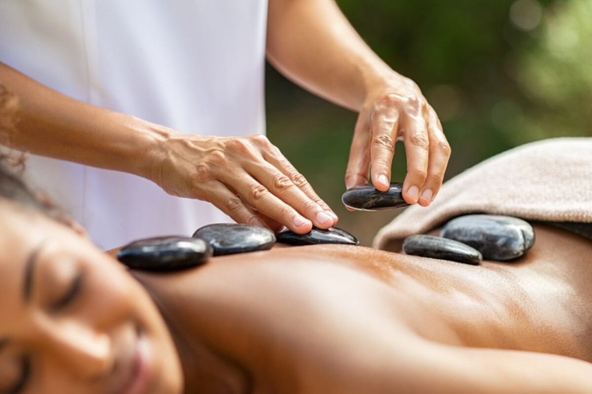 Masseuse hands placing hot stones